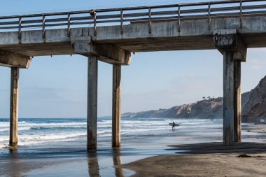 Yalnız bir erkek sörfçü bir sörf tahtası denize yakın bir beton İskelesi, La Jolla, Kaliforniya gerçekleştirdiği