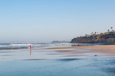 SOLANA BEACH, CALIFORNIA/USA - APRIL 22, 2018:  A small child stands alone on the shore at low tide by Fletcher Cove  Beach Park in San Diego.