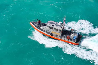 Key West, Florida / Usa - 12 Kasım 2019: Okyanus boyunca hızla ilerleyen ABD Sahil Güvenlik gemisindeki silahlı bir subayın görüntüsü.