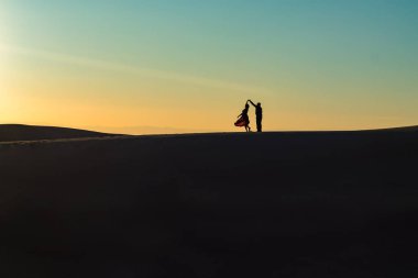 Gün batımında çölde dans eden bir çift.. 