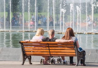 Şirket tarafından Gorki Park çeşme bankta dinleniyor. Moskova'da Gorki. Bir adam iki kadın arasında oturur ve hugs her ikisine de