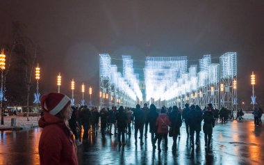 Moskova, Rusya - 1 Ocak 2017: Şenlikli aydınlatma ve bir sürü insan ana Vdnh Avenue yeni yıl arifesinde. Noel Baba, şapkalı kız siluet. Yağmurlu