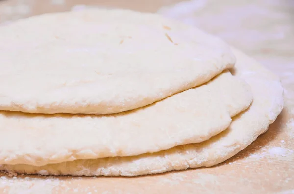 Masa de levadura de trigo crudo enrollada en tortas planas sobre una mesa — Foto de Stock