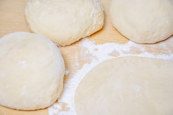 Raw wheat yeast dough rolled out into flat cakes on a table — Stock Photo, Image