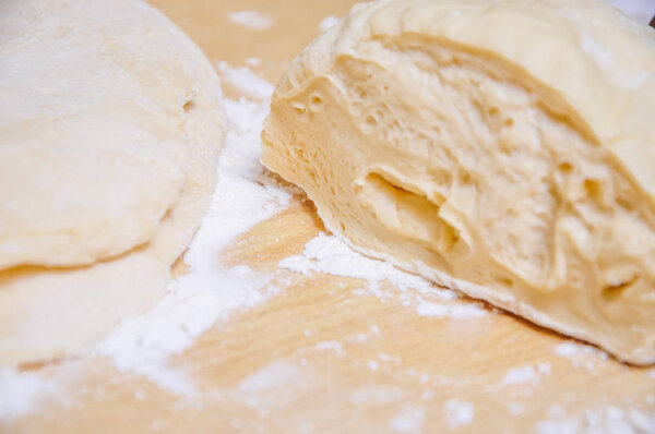 Raw wheat yeast dough on the table sprinkled with flour