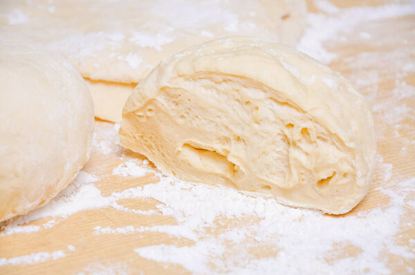 Raw wheat yeast dough on the table sprinkled with flour
