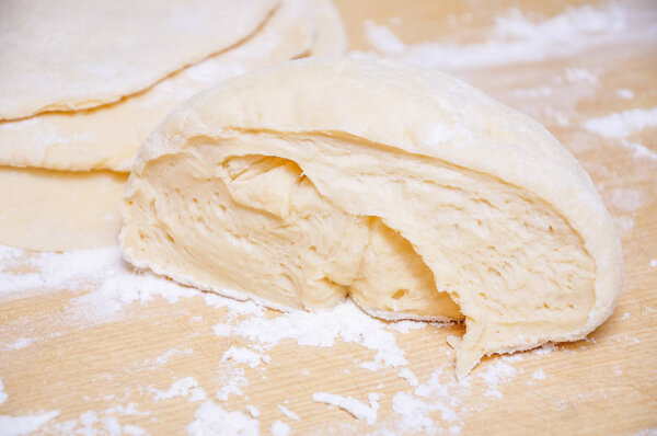 Raw wheat yeast dough rolled out into flat cakes on a table 