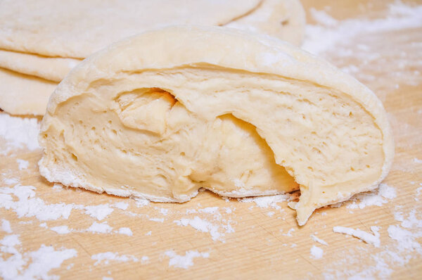 Raw wheat yeast dough rolled out into flat cakes on a table 