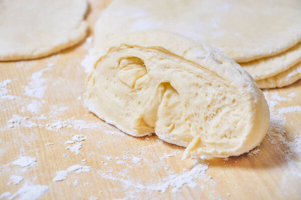 Raw wheat yeast dough rolled out into flat cakes on a table 