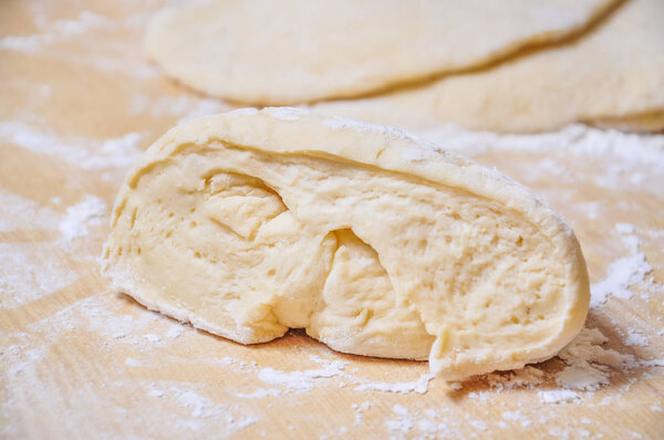 Raw wheat yeast dough rolled out into flat cakes on a table 