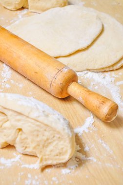 Haddelenmiş buğday hamur ve merdane ahşap bir masa üzerinde un ile silkeledi