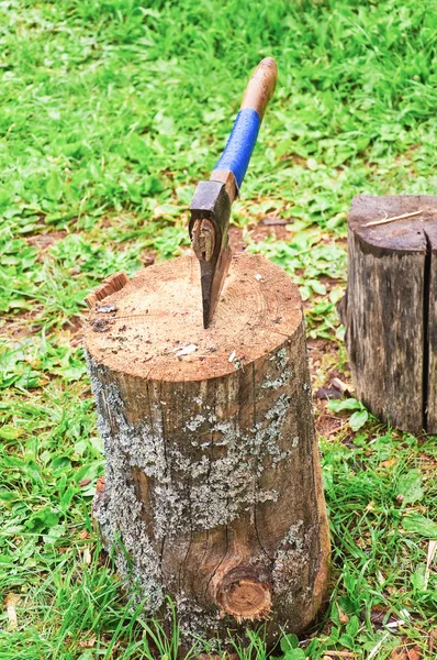 An old axe wrapped with duct tape stuck in a stump