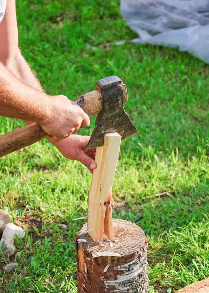 Cutting wood for kindling. Men\'s hands, axe and firewood