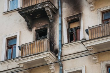 Yangından sonra evin cephe. Yanık daire çevresinde kurum duvarından kararmış. Pencere ve balkon alevler zarar