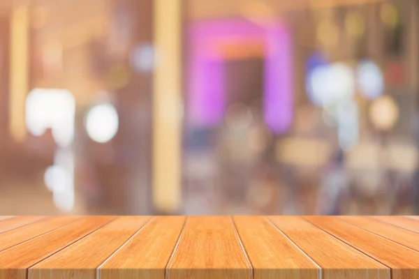 Σανίδα άδειο τραπέζι μπροστά θολή φόντο. Προοπτική καφέ ξύλο πάνω από blur σε εστιατόριο - μπορεί να χρησιμοποιηθεί για την επίδειξη ή μοντάζ σας προϊόντα. Κοροϊδεύετε για την προβολή του προϊόντος. — Φωτογραφία Αρχείου