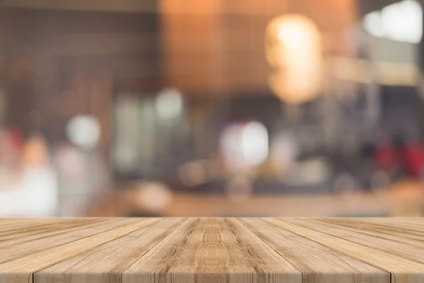 Σανίδα άδειο τραπέζι μπροστά θολή φόντο. Προοπτική καφέ ξύλο πάνω από blur σε εστιατόριο - μπορεί να χρησιμοποιηθεί για την επίδειξη ή μοντάζ σας προϊόντα. Κοροϊδεύετε για την προβολή του προϊόντος. — Φωτογραφία Αρχείου