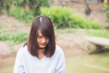 Parkta gülümseyen ve beyaz dişleriyle kameraya bakan bir kadın.