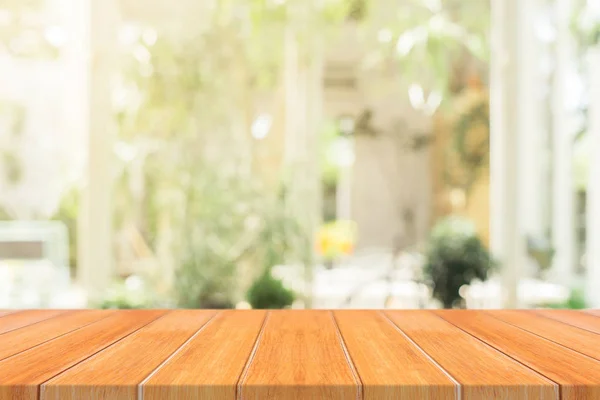 Tablero de madera mesa vacía sobre fondo borroso. Mesa de madera marrón perspectiva sobre desenfoque en el fondo de la cafetería - se puede utilizar la maqueta para la exhibición de productos de montaje o diseño diseño diseño visual clave. — Foto de Stock