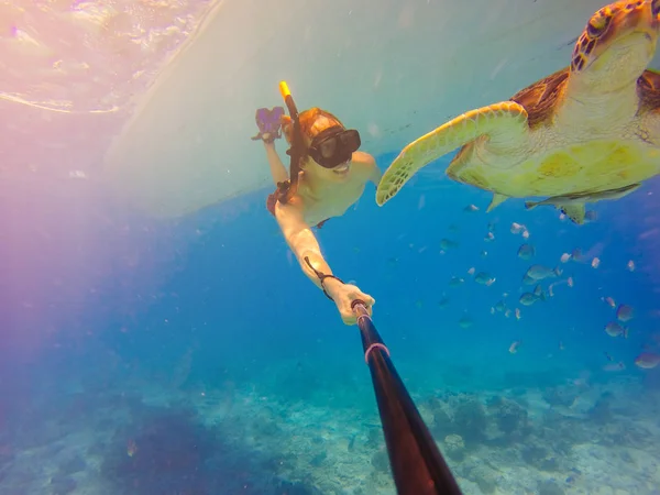 Tiro de selfie subaquático com pau de selfie. Cartão postal subaquático para animais selvagens marinhos. Uma tartaruga sentada em corais sob a superfície da água. Mar azul profundo. Tiro de ângulo largo . — Fotografia de Stock