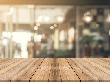 Ahşap tahta boş masa üstü bulanık arkaplan. Kahve dükkanının arka planındaki bulanıklık üzerine perspektif kahverengi ahşap masa - montaj ürünleri görüntüleme veya tasarım anahtar görsel düzeni için kullanılabilir.