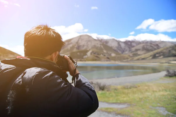 Photographer is taking a picture on top of a mountain landscape on the camera shoots.