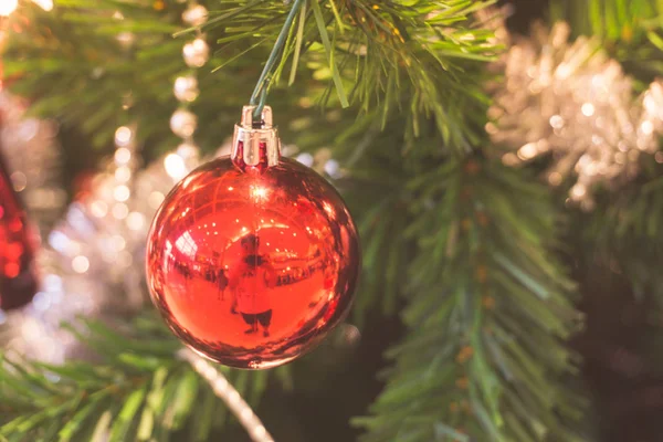 Closeup της κόκκινο μπιχλιμπίδι κρέμεται από ένα στολισμένο χριστουγεννιάτικο δέντρο. Εφέ φίλτρου ρετρό. — Φωτογραφία Αρχείου