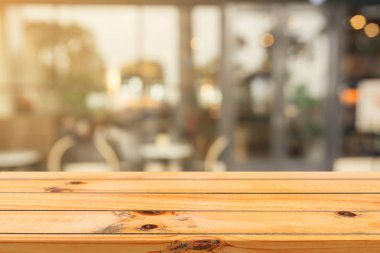 Ahşap tahta boş masa üstü bulanık arkaplan. Kahve dükkanının arka planındaki bulanıklık üzerine perspektif kahverengi ahşap masa - montaj ürünleri görüntüleme veya tasarım anahtar görsel düzeni için kullanılabilir.
