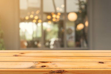 Ahşap tahta boş masa üstü bulanık arkaplan. Kahve dükkanının arka planındaki bulanıklık üzerine perspektif kahverengi ahşap masa - montaj ürünleri görüntüleme veya tasarım anahtar görsel düzeni için kullanılabilir.