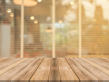 Ahşap tahta boş masa üstü bulanık arkaplan. Kahve dükkanının arka planındaki bulanıklık üzerine perspektif kahverengi ahşap masa - montaj ürünleri görüntüleme veya tasarım anahtar görsel düzeni için kullanılabilir.