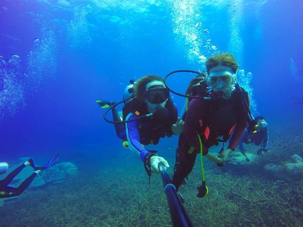 Casal subaquático mergulho selfie tiro com vara selfie. Mar azul profundo. Tiro de ângulo largo . — Fotografia de Stock