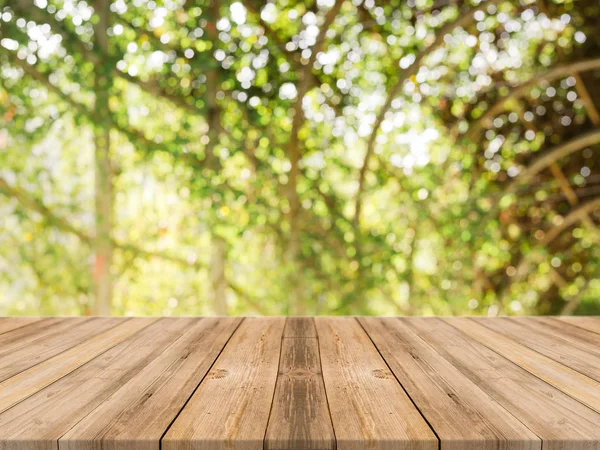 Holzbrett leerer Tisch vor verschwommenem Hintergrund. Perspektive brauner Holztisch über verschwommenen Bäumen im Waldhintergrund - kann als Attrappe zur Anzeige oder Montage Ihrer Produkte verwendet werden. Frühlingszeit. — Stockfoto