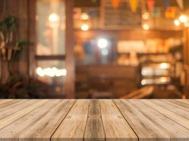 Ahşap tahta boş masa üstü bulanık arkaplan. Kahve dükkanının arka planındaki bulanıklık üzerine perspektif kahverengi ahşap masa - montaj ürünleri görüntüleme veya tasarım anahtar görsel düzeni için kullanılabilir.