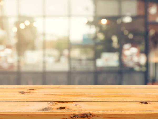 Tablero de madera mesa vacía sobre fondo borroso. Mesa de madera marrón perspectiva sobre desenfoque en el fondo de la cafetería - se puede utilizar la maqueta para la exhibición de productos de montaje o diseño diseño diseño visual clave. — Foto de Stock