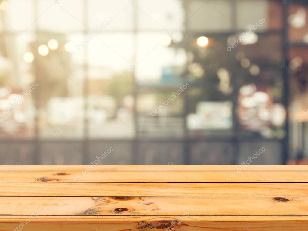 Wooden board empty table top on of blurred background. Perspective brown wood table over blur in coffee shop background - can be used mock up for montage products display or design key visual layout.