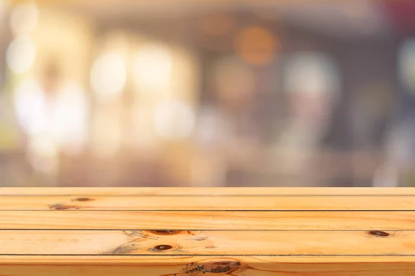 Tablero de madera mesa vacía sobre fondo borroso. Mesa de madera marrón perspectiva sobre desenfoque en el fondo de la cafetería - se puede utilizar la maqueta para la exhibición de productos de montaje o diseño diseño diseño visual clave. — Foto de Stock