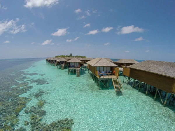 Vista aérea de una isla tropical en aguas turquesas. Lujosas villas sobre el agua en las maldivas del complejo de islas tropicales para vacaciones de vacaciones concepto de fondo - Aumentar el procesamiento de color . — Foto de Stock