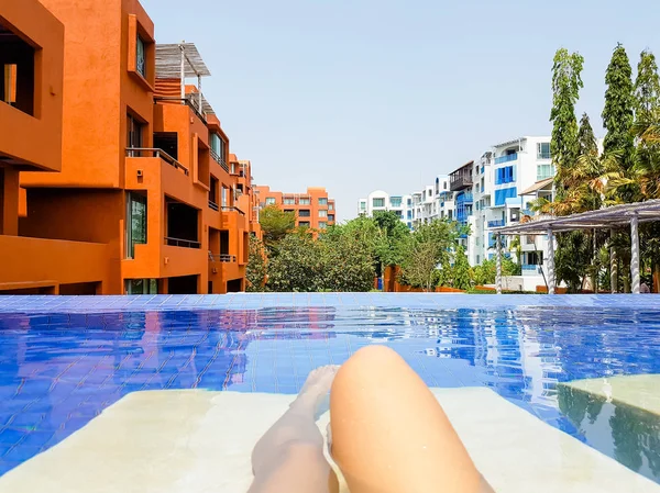 Woman lying on a lounger by the pool at the hotel. Girl at travel spa resort pool. Summer luxury vacation.