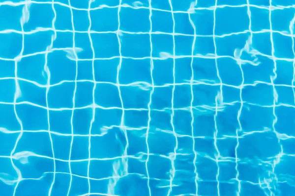 Wasser plätschert auf blau gefliestem Schwimmbadhintergrund. Blick von oben. — Stockfoto