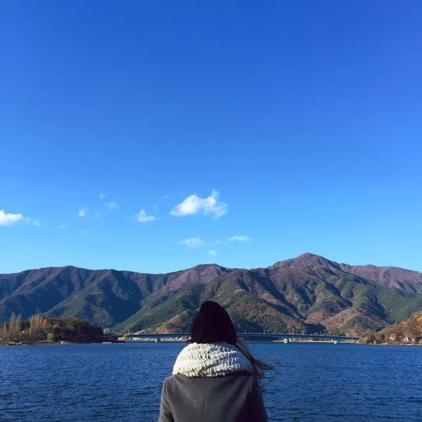 シュールで夢のような設定で湖の静かな水面の横に若い女性が立っています。ビンテージ フィルター効果を追加. — ストック写真