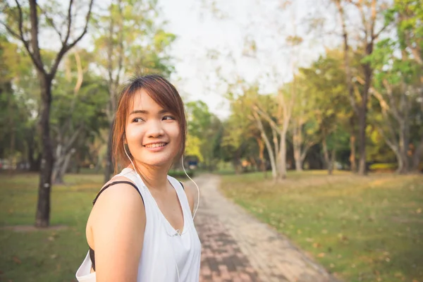 Happy sporty woman wearing smartphone armband and earphones before running in autumn. Female athlete listening music during fitness training outdoor. Vintage effect style pictures.