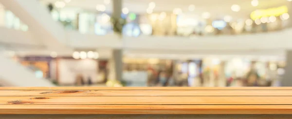 Placa de madeira mesa vazia fundo borrado. Mesa de madeira marrom perspectiva sobre borrão no fundo da loja de departamento, banner panorâmico pode ser usado para simular a exibição de produtos de montagem ou design . — Fotografia de Stock