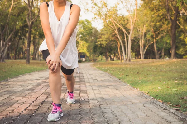 Young female stretching before fitness training session at the park. Healthy young woman warming up outdoors. She is stretching her arms and looking away,hi key. Vintage effect style pictures.