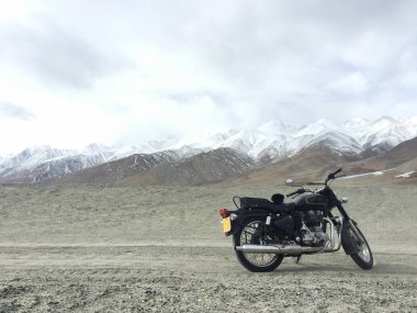 Sonsuz dağ bozkır Yaylası Ukok Altay Dağları Sibirya Rusya arka plan üzerinde bulutlu havalarda kayalıkbir platonun üzerinde duran bavul ile yalnız seyahat enduro motosiklet.