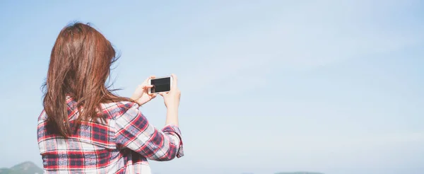 Takaisin näkymä nainen ottaa valokuvan älypuhelimen kamera horisontissa rannalla. Panoraamabanderolli . — kuvapankkivalokuva