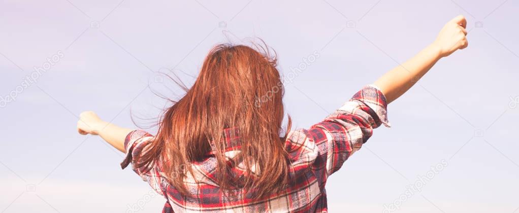 Happy freedom woman with open arms looking at blue sea horizon outdoors. Carefree person living a free life. Panorama horizontal banner crop for success and bliss concept.