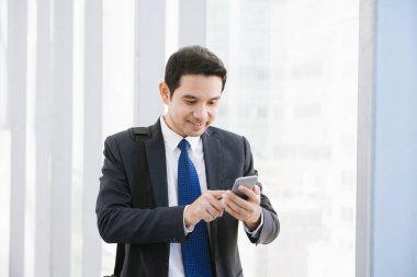 Adam akıllı telefon - havaalanında genç iş adamı. Smartphone ofis binası içinde mutlu gülümseyerek kullanarak rahat kentsel profesyonel iş adamı. Kapalı elbise giyen yakışıklı adam.