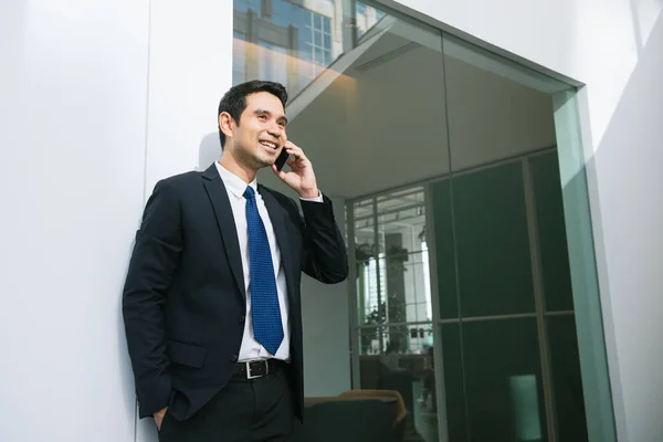Hombre de negocios guapo de traje hablando por teléfono en la oficina. — Foto de Stock