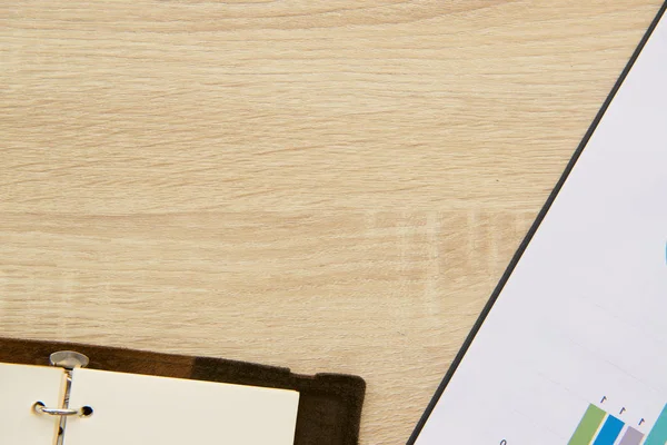 Office desk workplace with charts and book on wooden table. Top view with copy space