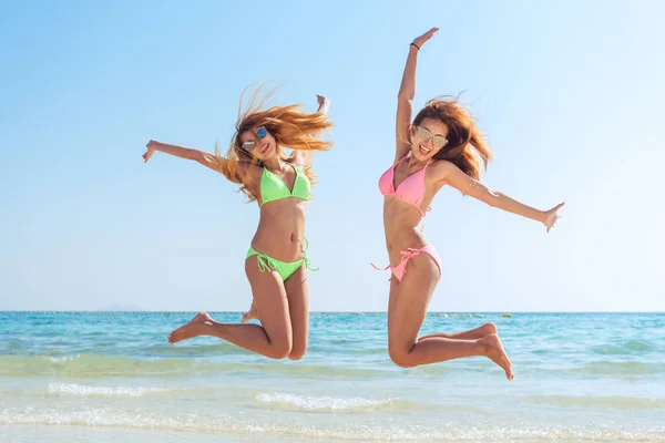 Glücklich Bikini zwei asiatische Frauen springen vor Freude und Erfolg auf perfekten weißen Sandstrand in der Karibik tropischen Urlaub. Ferienmädchen mit sexy schlanken sonnengebräunten Körper, der von Freiheit und Glück rennt. — Stockfoto