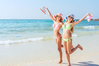 Mutlu bikini iki Asyalı kadınlar sevinç ve başarı mükemmel beyaz kum plaj üzerinde Karayip tropik tatil atlama. Tatil kızlar seksi ince güneş vücut çalışan özgürlük ve mutluluk.